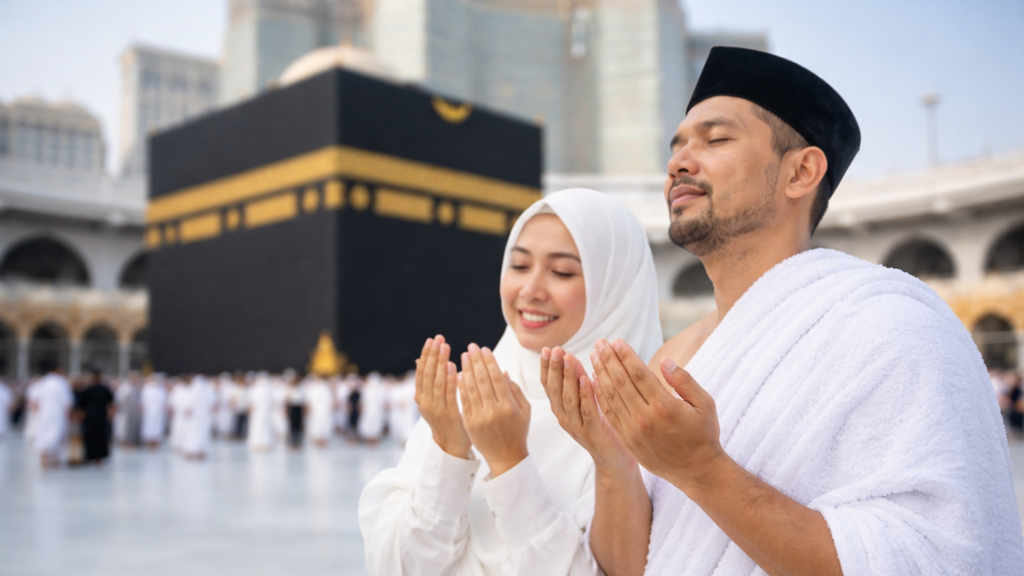 pasangan jamaah umroh sedang berdoa di depan ka'bah masjidil haram mekkah dengan pakaian ihram dan hijab putih
