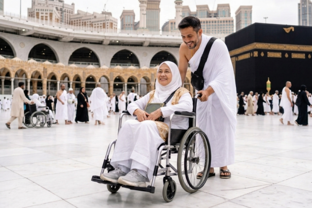 Pria berpakaian ihram mendorong ibu lansia di kursi roda dengan latar belakang Ka'bah dan Masjidil Haram Makkah, suasana ibadah umrah yang khidmat dan penuh kasih sayang.
