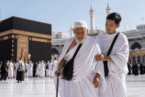 Seorang anak menuntun orang tua lanjut usia saat menjalankan ibadah umroh di depan Ka'bah dengan suasana khusyuk